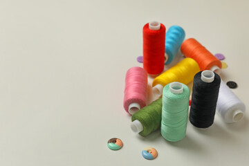 Sewing threads and buttons on white background, space for text