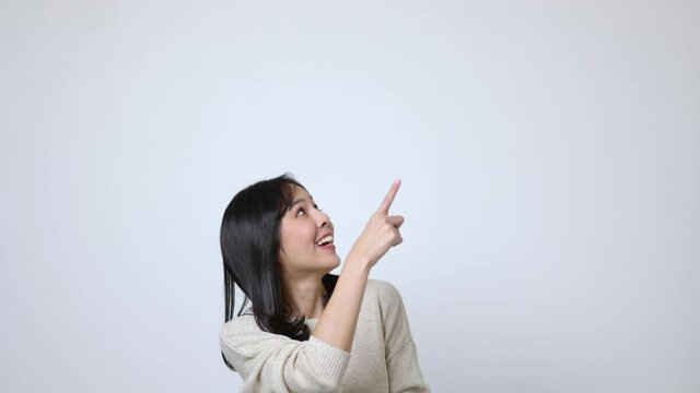 Attractive Beautiful asian woman pointing finger into blank space. Smiling female on isolated background.
