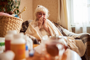 Old woman with flu blowing her nose in handkerchief