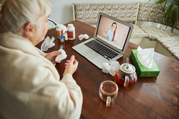 Fototapeta na wymiar Sick old woman talking with doctor through video call