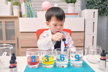 Little Asian kindergarten kid studying science, making Sugar Water Density Experiment with sugar, water and food coloring, Kid-friendly fun and easy science experiments at home concept
