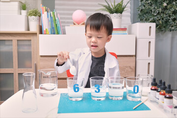 Little Asian kindergarten kid studying science, making Sugar Water Density Experiment with sugar, water and food coloring, Kid-friendly fun and easy science experiments at home concept