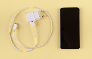 Mobile smartphone with charging on yellow background.