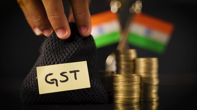 Bag with GST sticker on it placing infront of the stack of Coins and Indian flag as background - Concept goods and service indirect tax collection in India