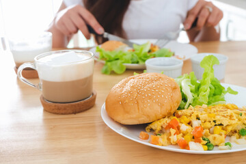 Breakfast omelettes, breads, hamburgers and vegetables on a white plate, eaten at the blurred back