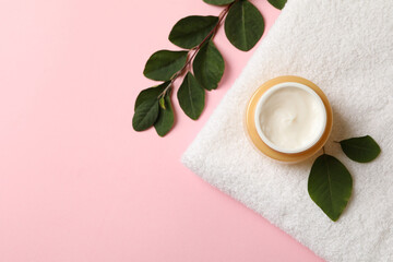 Obraz na płótnie Canvas Towel with jar of cosmetic cream on pink background