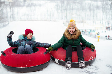Children are loving tubing down a steep hill during a snowly winter.