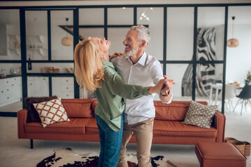 Nice couple dancing in the room and looking happy