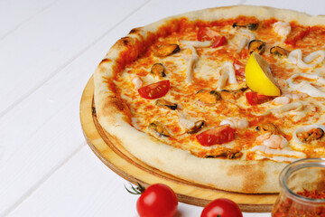 Seafood pizza on board on white wooden table