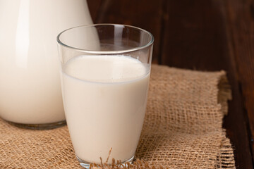 Glass pitcher of milk on old wooden table