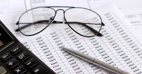 Financial graphs and charts analysis with calculator, pen and glasses