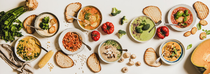 Flat-lay of vegetarian creamy homemade soup in plates with bread slices over white plain table...