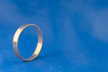 wedding gold ring close-up standing on a wide edge, on a blue background in a haze