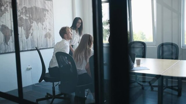 Viev through the glass of young business people in formal clothes that working in the office.