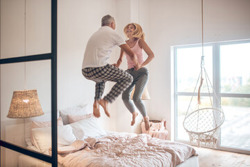 Mature couple jumping on the bed and feeling awesome
