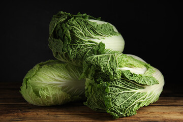 Fototapeta premium Fresh ripe Chinese cabbages on wooden table against black background