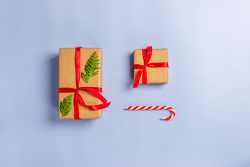 Gift boxes wrapped with paper kraft, red ribbon, thuja twigs, candy on sticks on a light background. Top view. Presents for the holiday, Christmas.