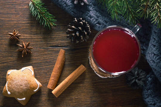 Hot cranberry punch or tea with spices cinnamon sticks and anise stars decorated fur tree brunches and ginger bread on wooden background. Winter and Christmas evening. Top view.