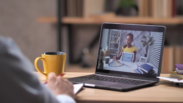 Close-up of video chat on laptop computer, african american female interior designer and customer remotely discussing floor plan of house and options for painting walls using tablet and color palette