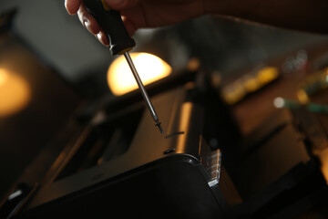 Repairman with screwdriver fixing modern printer, closeup