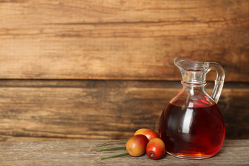 Palm oil in glass jug and fresh fruits on wooden table. Space for text