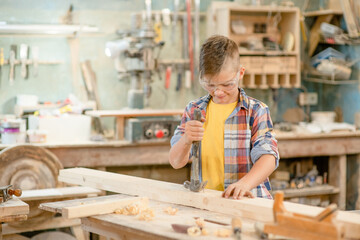 Young boy enjoys a carpentry hobby in the workshop. Empty space for text