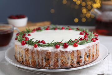 Traditional Christmas cake decorated with rosemary and cranberries on table, closeup