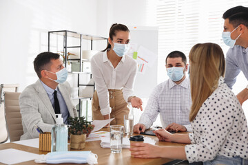 Group of coworkers with protective masks in office. Business meeting during COVID-19 pandemic