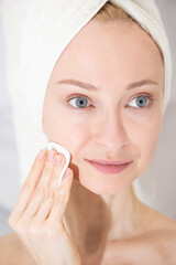 Young woman with a towel washes her face. Personal care concept.