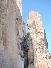 Natural picture of the invincible stone wall of the canyon on a background of clear blue sunny sky.