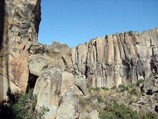Natural picture of the invincible stone wall of the canyon on a background of clear blue sunny sky.