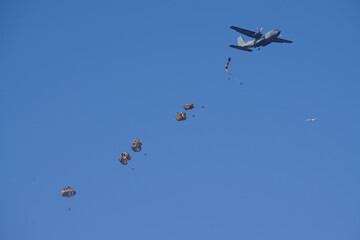 Fototapeta na wymiar air force plane dropping army parachute jumpers on a clear blue day