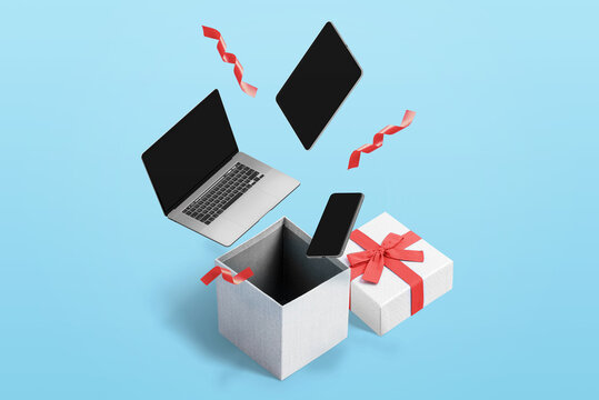 Concept of buying tech products and making gifts for Christmas and New Year. Laptop, tablet and phone drop in gift box