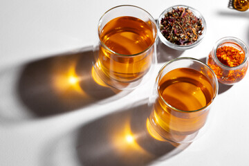 Glass cup of tea and dry tea leaves on white table