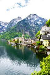 Fototapeta na wymiar View of buildings and old church along the coastline. View of the mountains and monuments of the city. Hallstatt, Austria