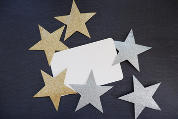 Obraz premium New year concept. A blank card with gold and silver stars. winter holiday decoration on dark background. 年末年始、新年コンセプト、星のデコレーションとカード