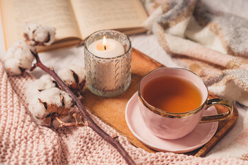 Obraz na płótnie Canvas Details of still life in the home interior of living room. Sweater, cup of tea, cotton, cozy, book, candle. Moody. Cosy autumn winter concept. Decoration, vintage with glow bokeh.