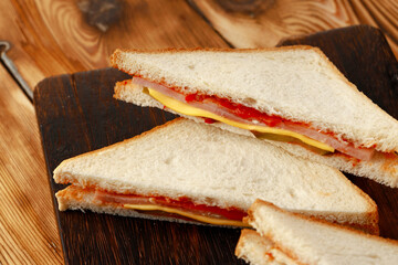 Sandwiches cut into halves on wooden cutting board with napkin