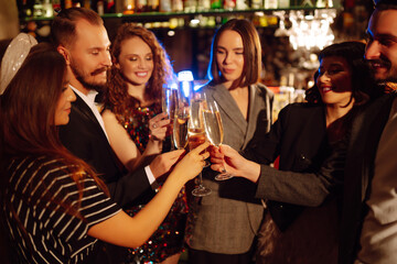 Group of happy people clinking glasses of champagne at party. Young friends celebrating winter holiday together with champagne. Party, celebration, drink, birthday concept.