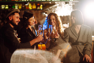 Group of happy people clinking glasses of champagne at party. Young friends celebrating winter holiday together with champagne. Party, celebration, drink, birthday concept.