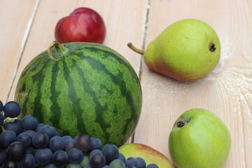 Watermelon, grapes, pear and apple on the background of the boards.