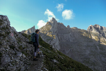 A top down view on the narrow trail along lose stones. There are sharp mountains and high peaks around. Dangerous mountain climbing. Bright day. Serenity and freedom.