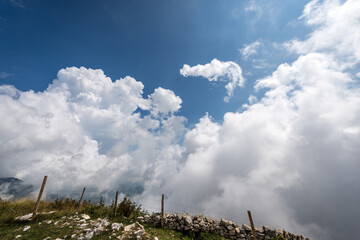 Beautiful cumulus clouds (cumulonimbus) on blue sky in mountain, Monte Baldo, Mountain range between Lake Garda and Adige Valley. Verona province, Veneto, Italy, Europe.