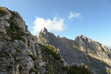 Fototapeta premium A panoramic view on Alpine slopes in Austria. There are sharp ans steep mountains and high peaks around. The Alpine slopes are almost barren, just moss overgrowing the slopes. Serenity and freedom.