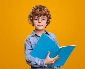 Clever schoolboy with textbook looking at camera