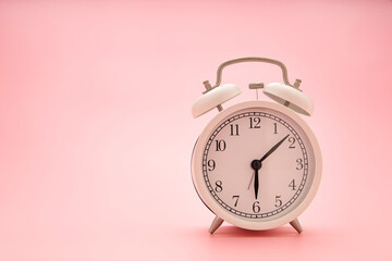 Close up a white clock on a pink background. Concept image.