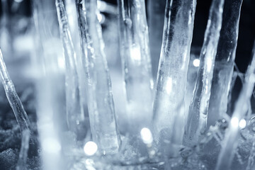 Close up crystal icicles standing in snow at dark night