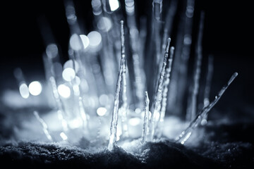 Naklejka na ściany i meble illuminated winter stalagmite icicles in snow at dark night
