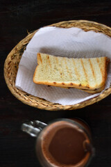 A slice of toast in a basket and a cup of warm chocolate on the table. menu for a healthy breakfast