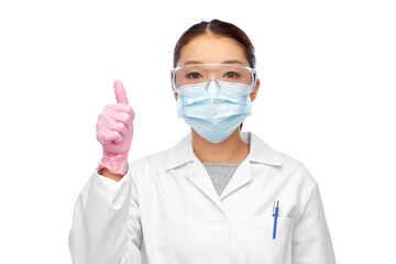 health, medicine and pandemic concept - young asian female doctor or scientist wearing goggles and face protective medical mask for protection from virus disease showing thumbs up
